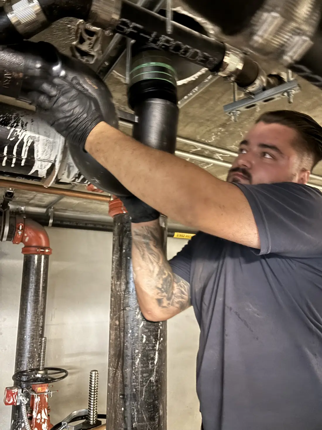 Flash Plumbing technician fitting a new drain pipe overhead
