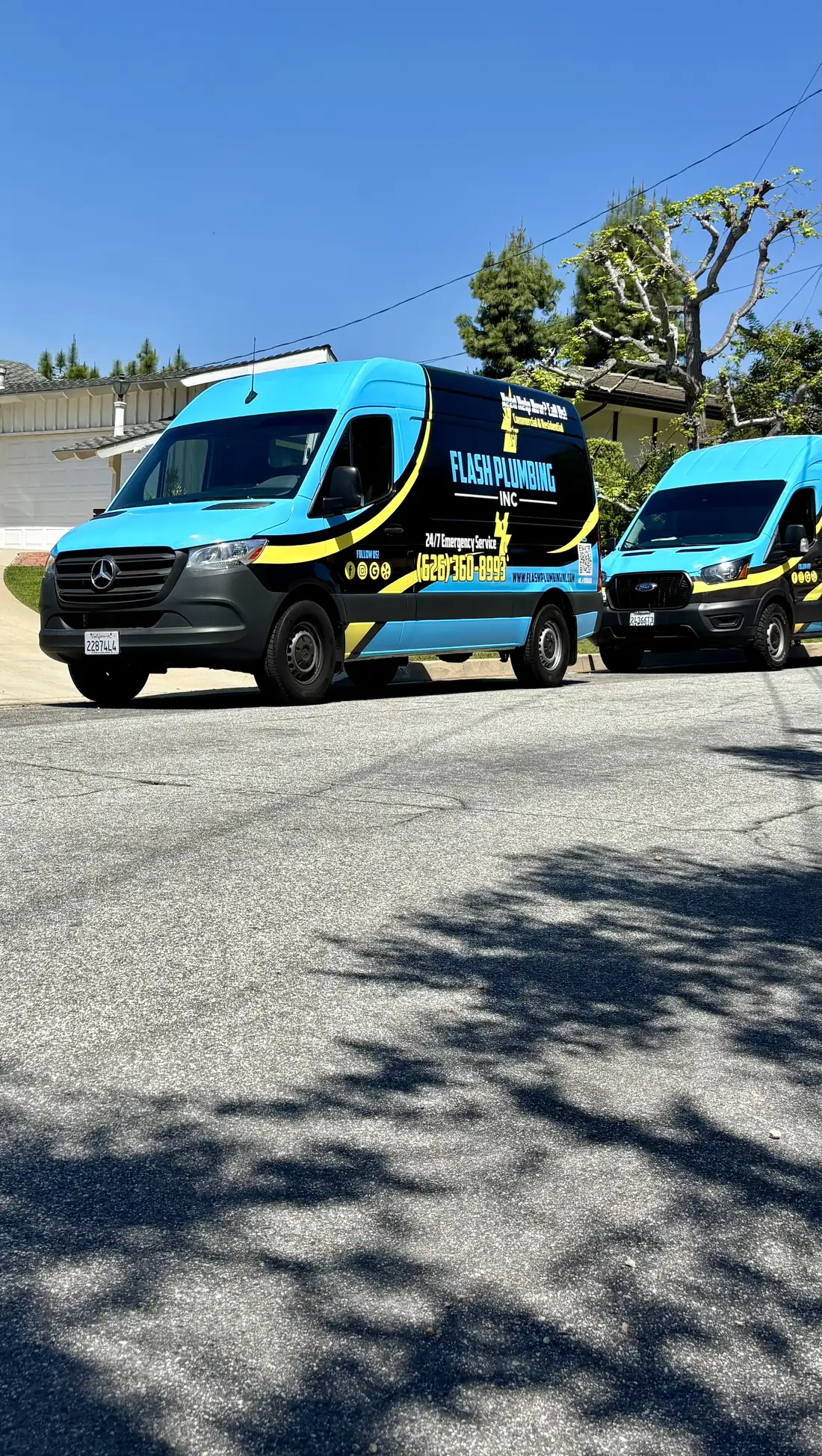 Two Flash Plumbing vans parked on a residential street