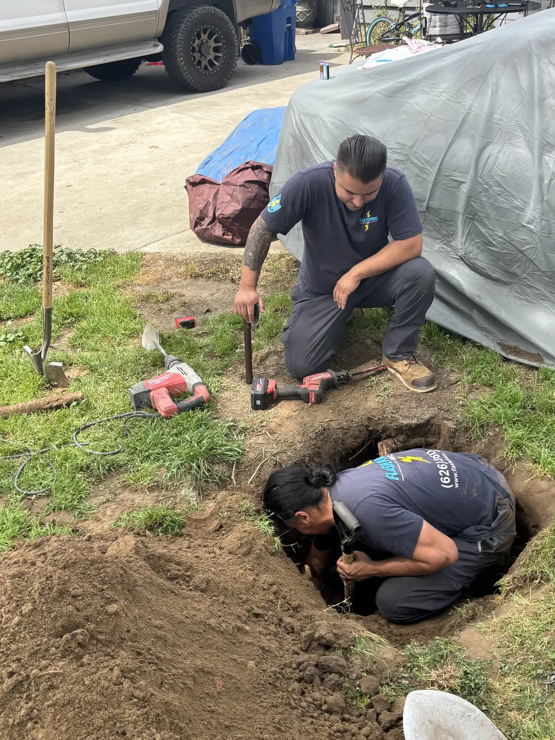 Two Flash Plumbing technicians digging down to a sewer line in a front yard