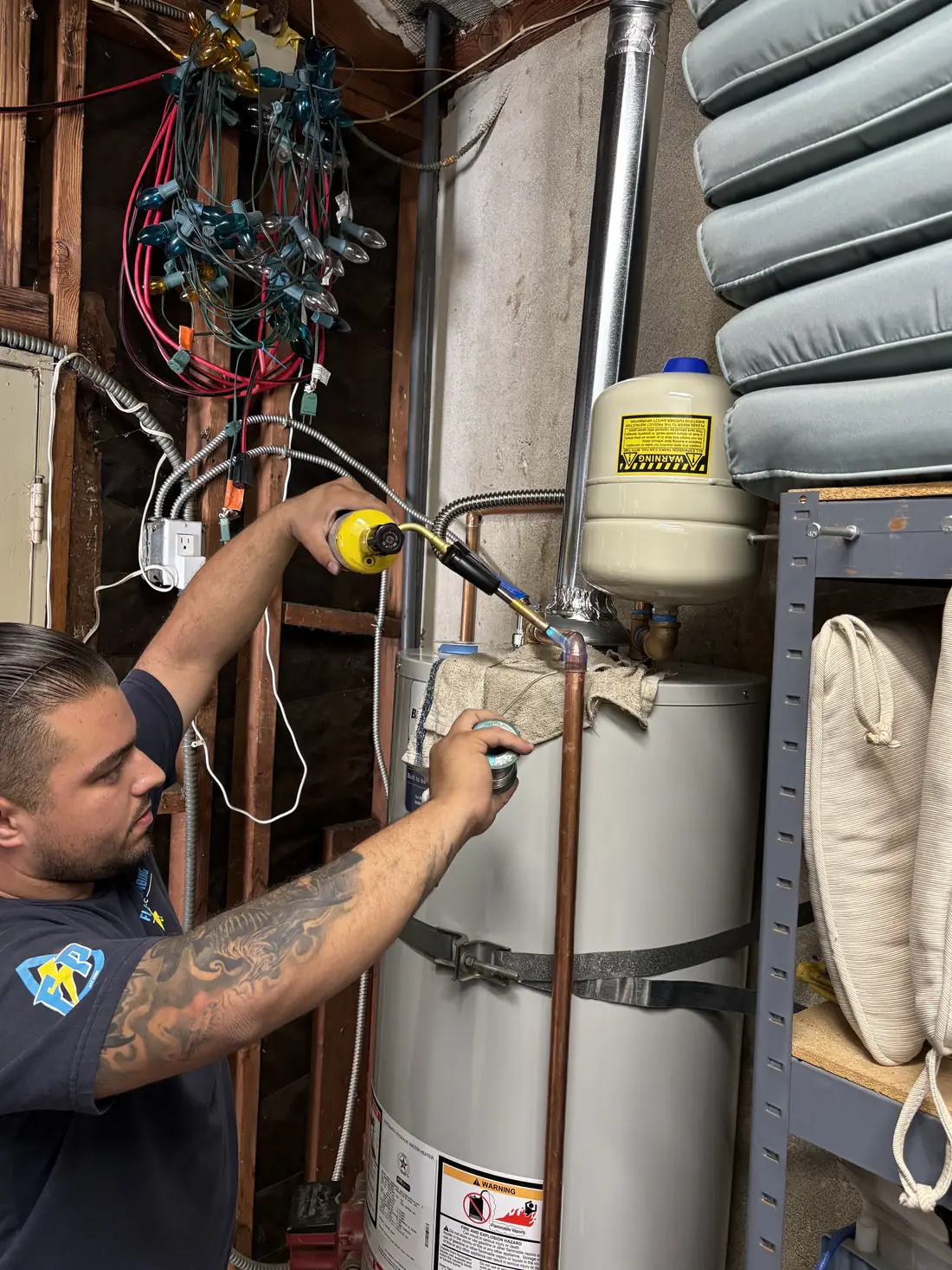 Flash Plumbing technician servicing a gas tank water heater with an expansion tank